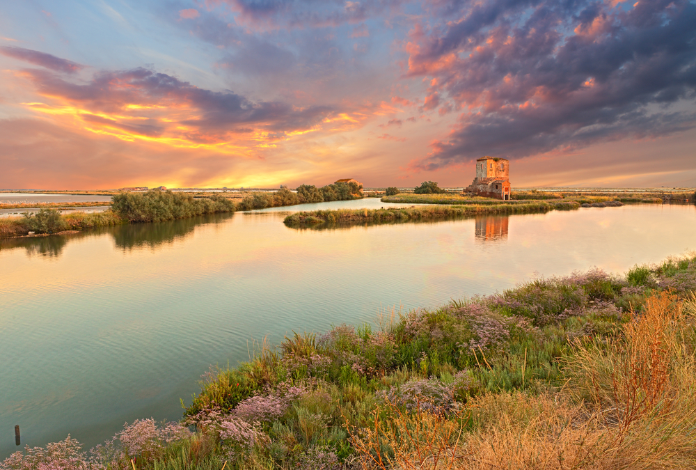 Comacchio, Ferrara, Emilia Romagna, Itália: paisagem ao pôr do sol do pântano com ruínas de uma casa antiga - a lagoa na reserva natural Parque Delta do Pó